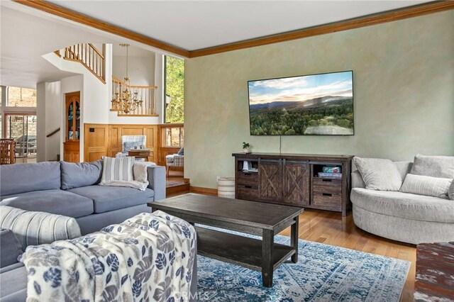 living room featuring ornamental molding, light hardwood / wood-style floors, and a notable chandelier