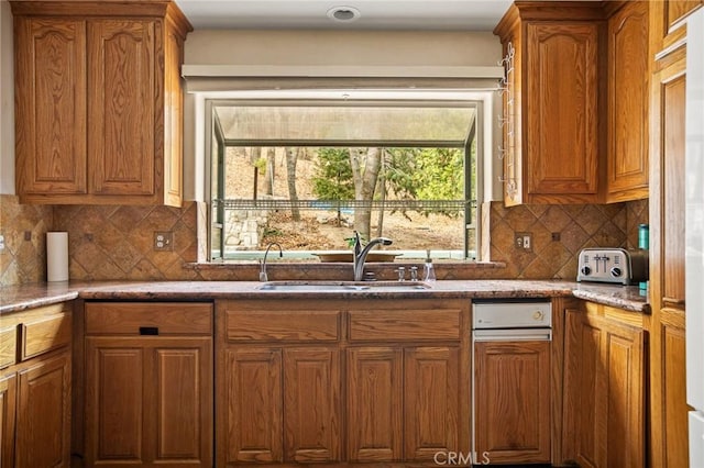 kitchen featuring sink, backsplash, and dark stone counters