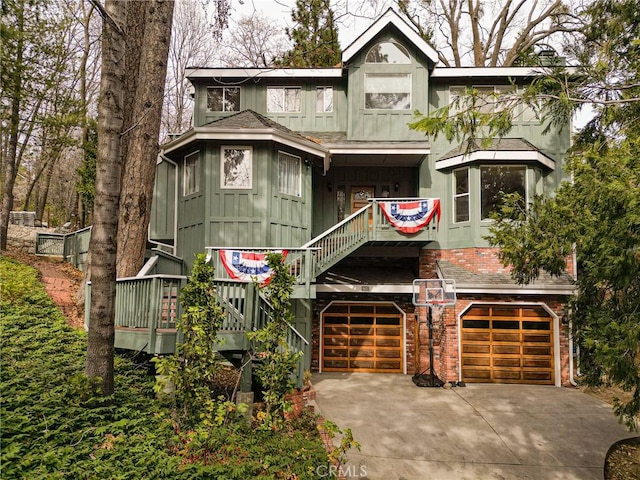 view of front of home featuring a garage, driveway, a shingled roof, board and batten siding, and brick siding