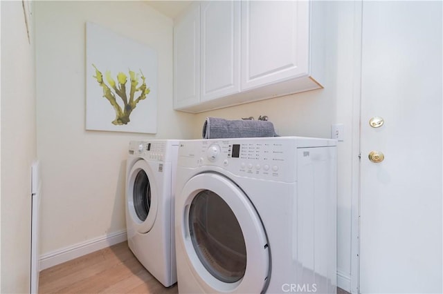 laundry room with cabinets, washing machine and clothes dryer, and light hardwood / wood-style flooring