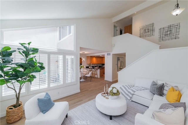 living room with light hardwood / wood-style floors and high vaulted ceiling