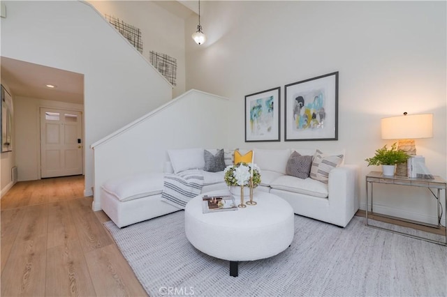 living room featuring a towering ceiling and light hardwood / wood-style flooring