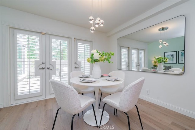 dining area with a chandelier, french doors, light hardwood / wood-style flooring, and a healthy amount of sunlight