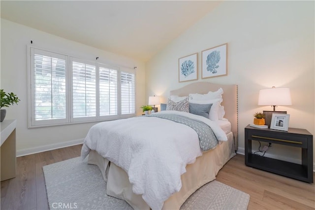 bedroom featuring light hardwood / wood-style floors and lofted ceiling