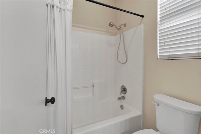 bathroom featuring toilet and tiled shower / bath