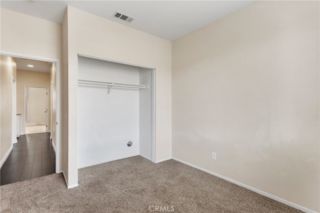 unfurnished bedroom featuring dark carpet and a closet