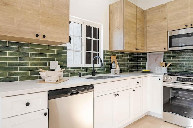 kitchen featuring tasteful backsplash, white cabinetry, appliances with stainless steel finishes, and sink