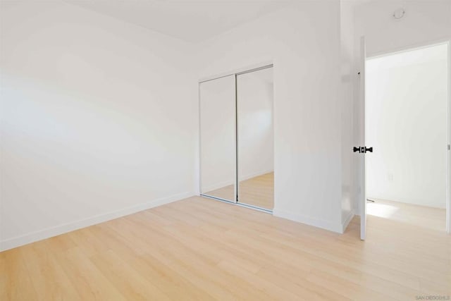 unfurnished bedroom with light wood-type flooring and a closet