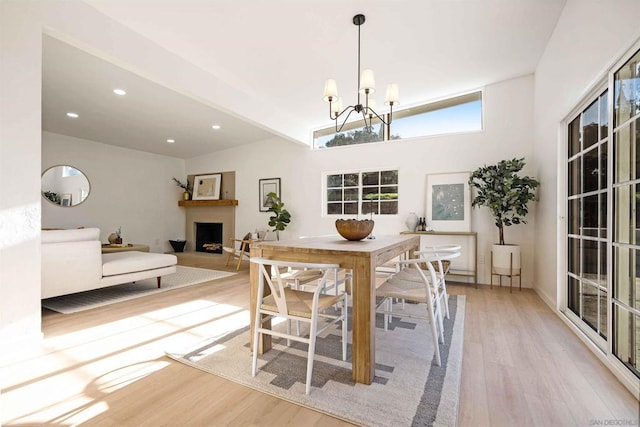 dining space featuring lofted ceiling, a notable chandelier, and light hardwood / wood-style flooring