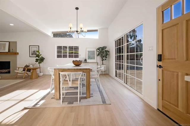 dining area with light hardwood / wood-style floors, a chandelier, and a high ceiling