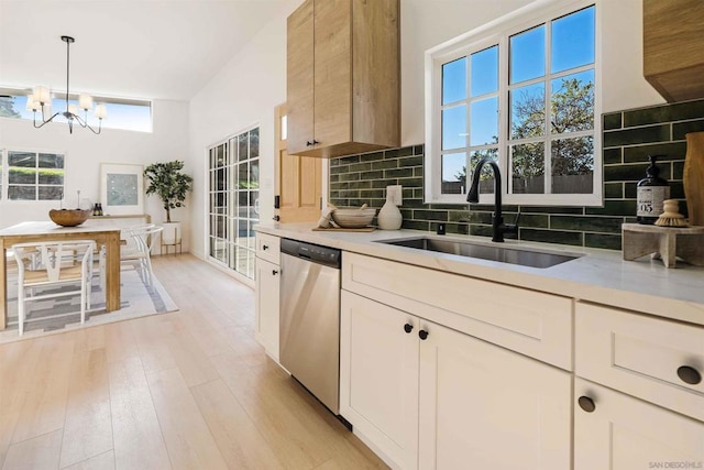 kitchen with pendant lighting, sink, dishwasher, decorative backsplash, and a chandelier