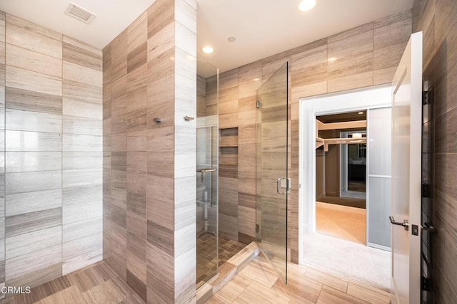 bathroom with an enclosed shower and tile walls