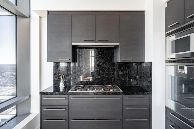 kitchen featuring backsplash, dark stone counters, and range hood