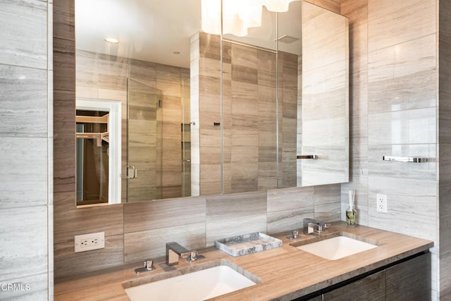 bathroom with backsplash, vanity, a shower with shower door, and tile walls