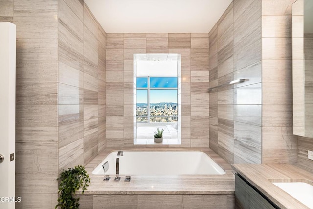 bathroom with vanity, tiled bath, and tile walls