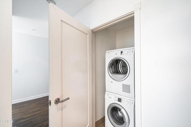 laundry area with stacked washing maching and dryer and dark hardwood / wood-style floors