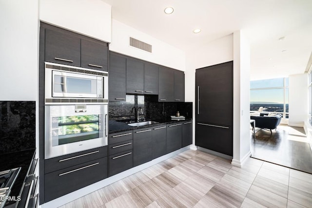 kitchen featuring backsplash, sink, light tile patterned floors, and stainless steel appliances