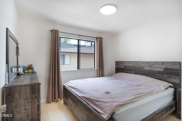 bedroom with a textured ceiling, light hardwood / wood-style floors, and pool table