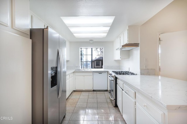 kitchen with kitchen peninsula, appliances with stainless steel finishes, sink, white cabinetry, and light tile patterned flooring