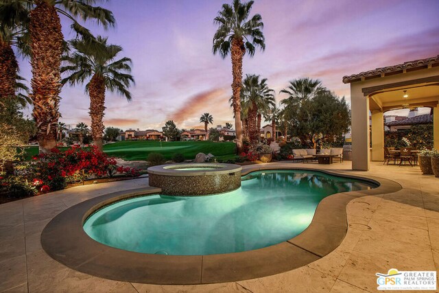 pool at dusk with an in ground hot tub and a patio