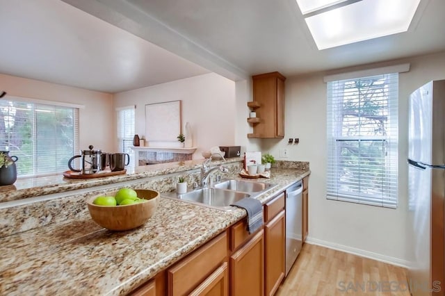 kitchen featuring appliances with stainless steel finishes, light hardwood / wood-style floors, sink, and a wealth of natural light