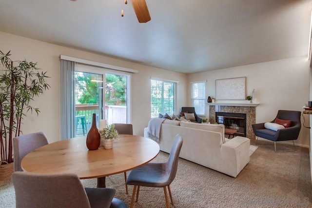 carpeted dining area featuring ceiling fan and a fireplace