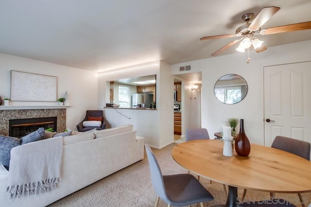 living room featuring ceiling fan, a fireplace, and light carpet