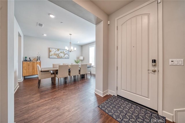 entryway with dark wood-type flooring and a notable chandelier