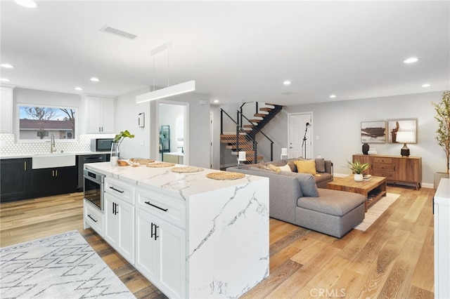 kitchen with a center island, white cabinets, sink, light hardwood / wood-style flooring, and tasteful backsplash