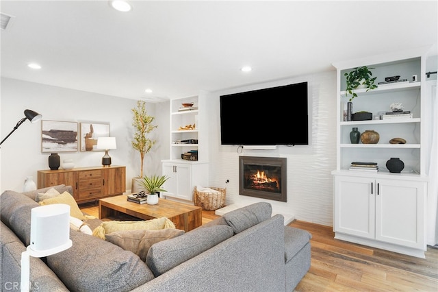 living room featuring built in features and light wood-type flooring