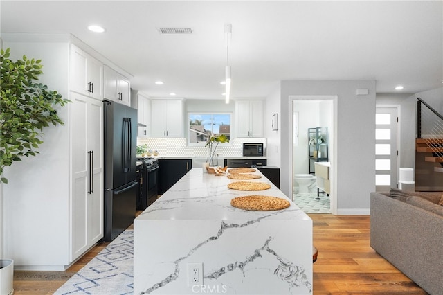 kitchen with light wood-type flooring, a center island, white cabinets, and black appliances