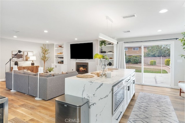 living room with built in shelves and light wood-type flooring