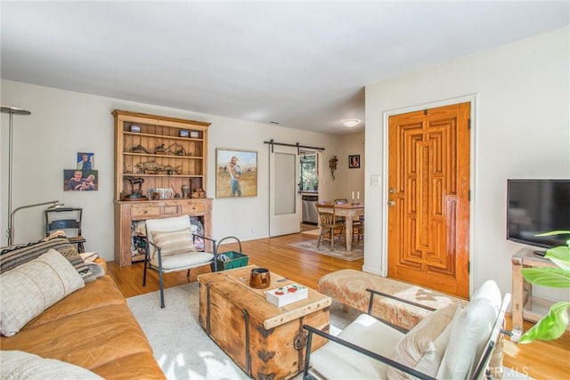 living room with a barn door and light hardwood / wood-style floors