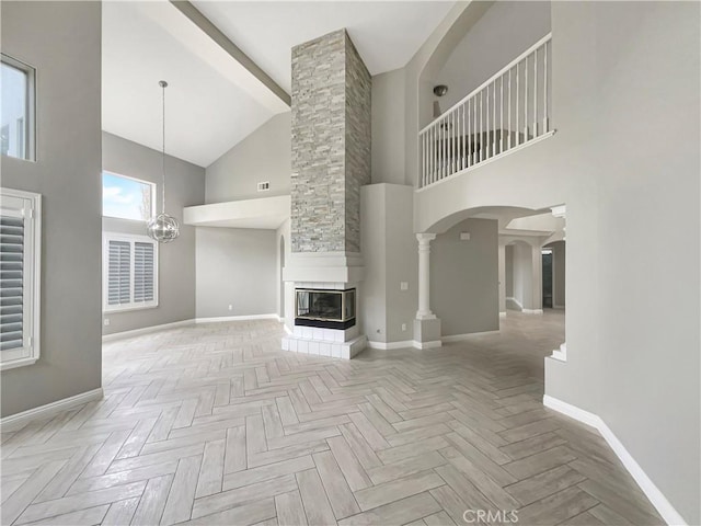 unfurnished living room with light parquet flooring, a towering ceiling, a chandelier, and a fireplace