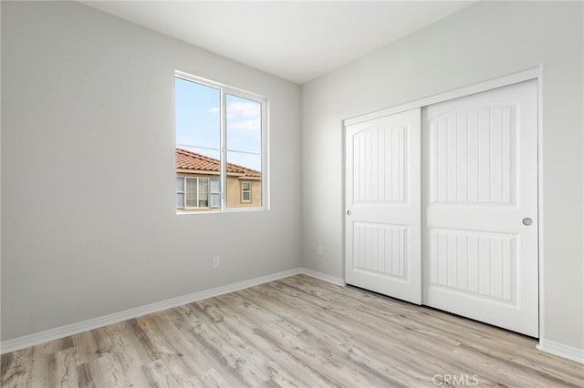 unfurnished bedroom with light wood-type flooring and a closet