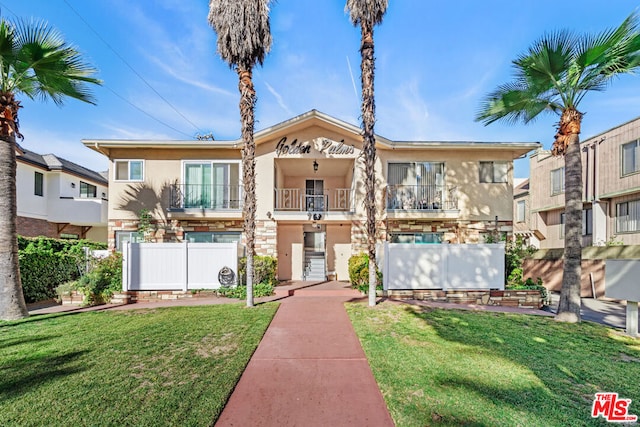 view of front of home with a front yard and a balcony