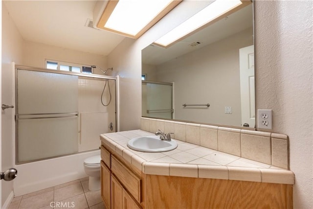 full bathroom featuring tile patterned flooring, vanity, toilet, and combined bath / shower with glass door