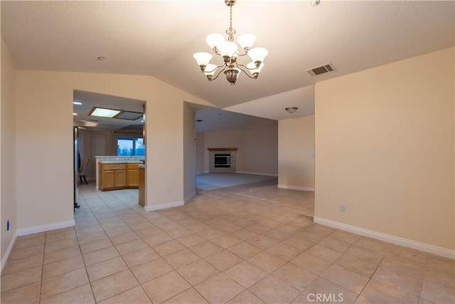 interior space with a notable chandelier, light tile patterned floors, and vaulted ceiling