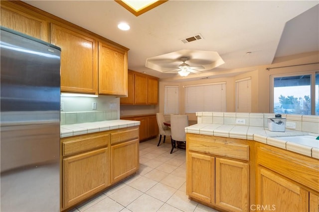 kitchen featuring tile countertops, stainless steel fridge, ceiling fan, and light tile patterned flooring