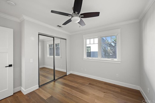 unfurnished bedroom featuring hardwood / wood-style floors, a closet, ceiling fan, and crown molding