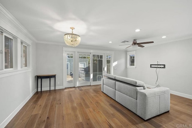 living room featuring crown molding, wood-type flooring, and ceiling fan with notable chandelier