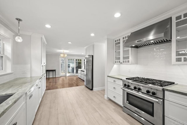 kitchen with white cabinets, wall chimney exhaust hood, backsplash, and stainless steel appliances