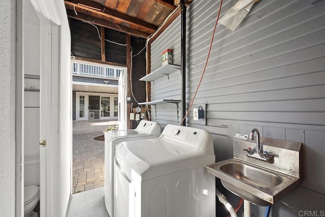 washroom featuring separate washer and dryer, sink, and wooden walls