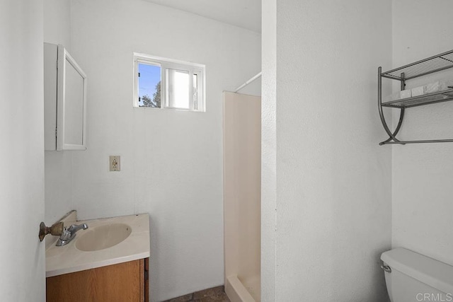 bathroom featuring vanity, toilet, and walk in shower