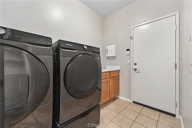 washroom with washer and dryer, light tile patterned flooring, and cabinet space