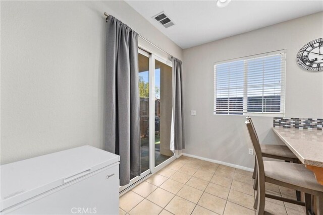 unfurnished dining area with light tile patterned floors and baseboards