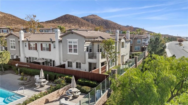 back of house featuring a patio, stucco siding, a chimney, and a mountain view