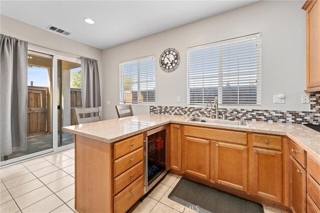 kitchen featuring wine cooler, a peninsula, backsplash, light tile patterned floors, and recessed lighting