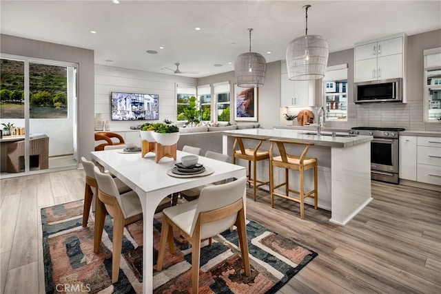 dining space featuring ceiling fan, a healthy amount of sunlight, light wood-type flooring, and sink