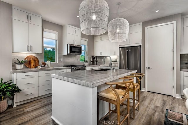 kitchen featuring a center island with sink, white cabinetry, sink, and appliances with stainless steel finishes